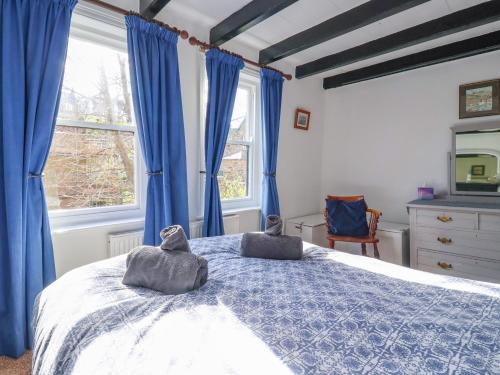 a bedroom with blue curtains and a bed with two towels on it at Roseberry Cottage in Whitby