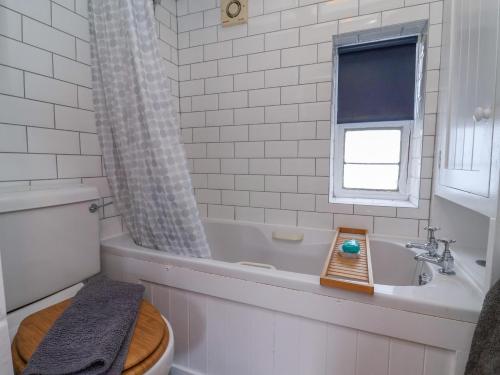a bathroom with a tub and a toilet and a sink at Roseberry Cottage in Whitby