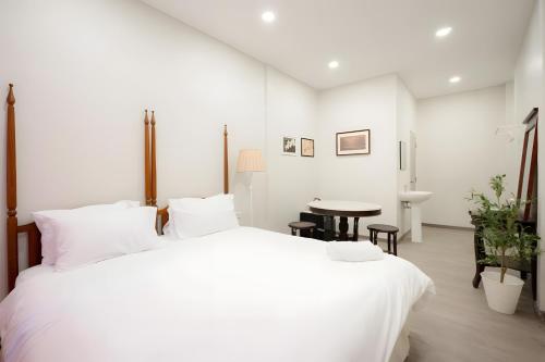 a white bedroom with a large bed and a table at xxCASA Dragon Yaowarat - MRT วัดมังกร in Samphanthawong