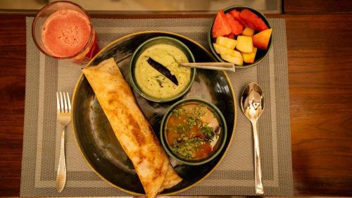 a black plate of food with dip and a burrito and fruit at Luho 6 off Sarjapur Road in Bengaluru