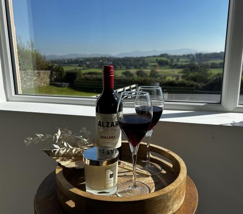 a bottle of wine and two glasses on a table at Luxury Cottage, views of the Lakes with Hot Tub in Cockermouth