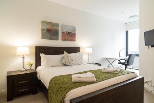 a bedroom with a large bed with a green blanket at AKOM AT Docklands in Melbourne