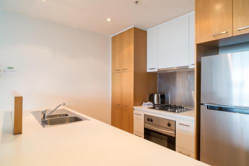a kitchen with a sink and a refrigerator at AKOM AT Docklands in Melbourne