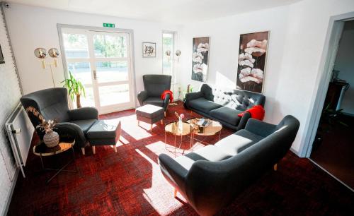 a living room with couches and chairs and a table at Hotel Falken in Videbæk