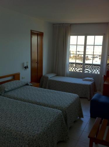 Habitación de hotel con 2 camas y ventana en Hotel Pinzon, en Baiona