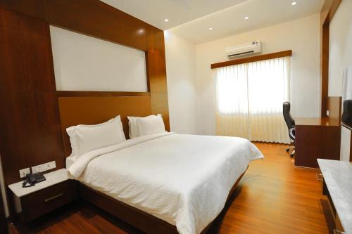 a bedroom with a large white bed and a window at Hotel Lakshmi Towers in Kāngayam