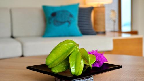 a plate of pickles and a flower on a table at The Uza Terrace Beach Club Villas in Yomitan