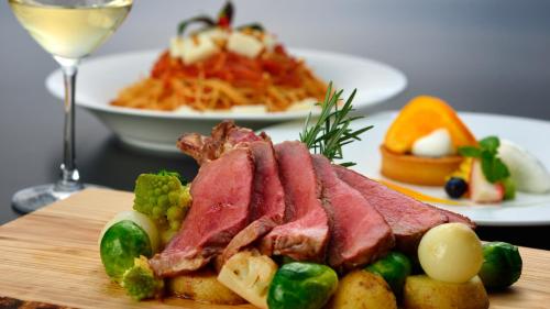 a plate of meat and vegetables and a glass of wine at The Uza Terrace Beach Club Villas in Yomitan