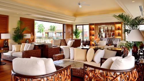a lobby with white couches and tables and windows at The Uza Terrace Beach Club Villas in Yomitan