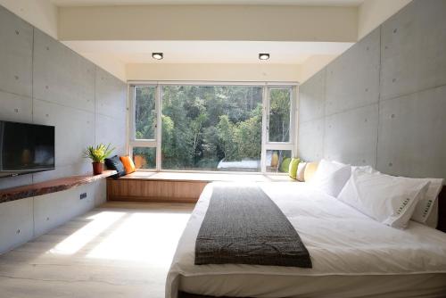 a bedroom with a large bed and a large window at 日月潭山慕藝旅 Sun Moon Inn in Yuchi