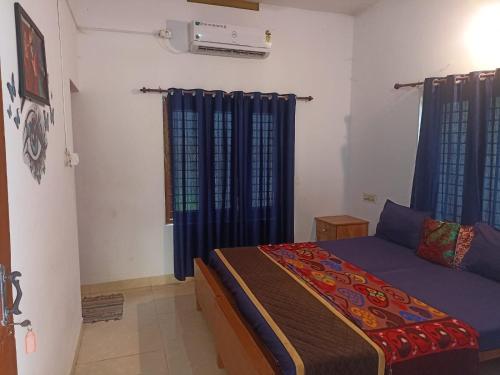 a bedroom with a bed with blue drapes at The Lungi Vibe in Varkala