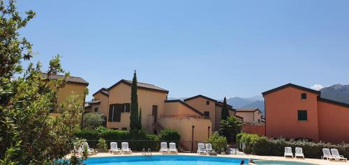 - une piscine en face de certains bâtiments dans l'établissement Duplex 4-6 p, Terrasses, Piscine, climatisé, Lozari, Corse, à Belgodère