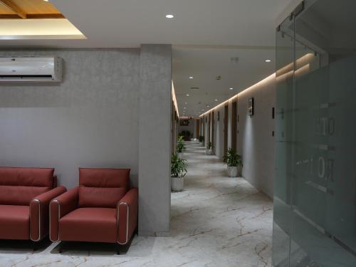 a waiting room with red couches and a corridor at Hotel Skyro Inn in Gandhinagar