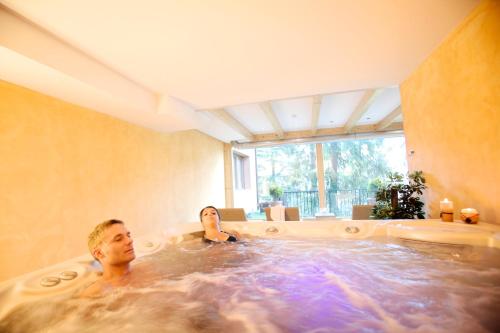 um par de pessoas numa banheira de hidromassagem em Hotel Caminetto em Folgarida