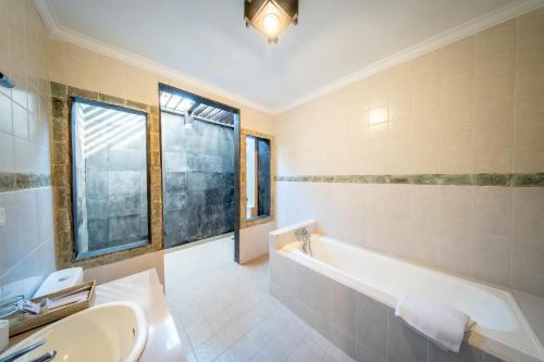 a bathroom with a tub and a sink at The Tukad Villa in Seminyak