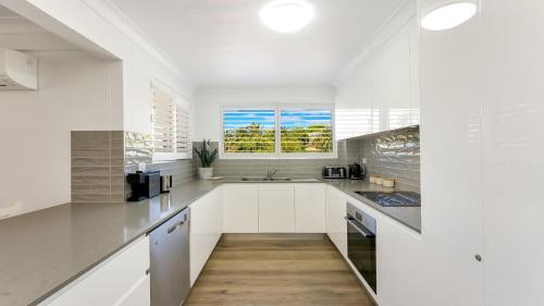 a kitchen with white cabinets and a window at Terrigal Bay #13 Pool, Wifi, Short Walk To Beach Accom Holidays in Terrigal