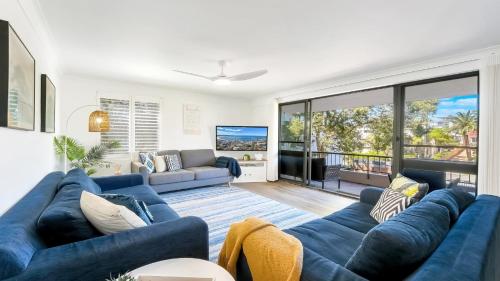 a living room with blue couches and a large window at Terrigal Bay #13 Pool, Wifi, Short Walk To Beach Accom Holidays in Terrigal