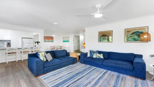 a living room with two blue couches and a kitchen at Terrigal Bay #13 Pool, Wifi, Short Walk To Beach Accom Holidays in Terrigal