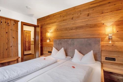 two beds in a room with wooden walls at Gästehaus Panorama - Appartement 1 in Reit im Winkl