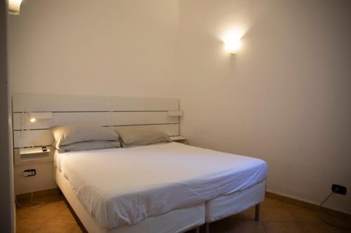 a bedroom with a white bed with a light on the wall at Dimora San Bartolomeo in Bari