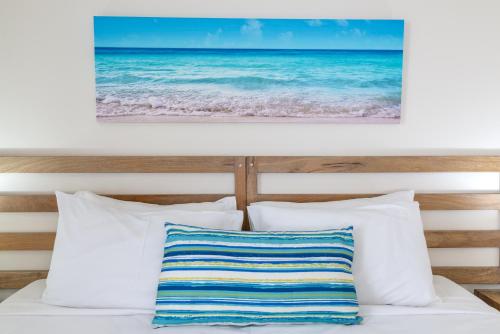 a bed with white pillows and a picture of the ocean at Meridian at Port Douglas - Adults Only in Port Douglas