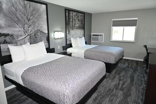ein Hotelzimmer mit zwei Betten und einem Fenster in der Unterkunft Super 8 by Wyndham Higginsville in Higginsville