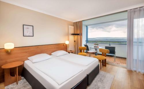 a hotel room with a bed and a large window at Wyndham Garden Lahnstein Koblenz in Koblenz