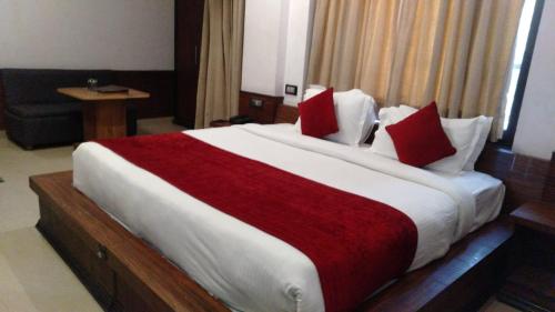 a bedroom with a large bed with red and white pillows at Hotel Holiday Hill Mcleodganj-Near to Dalai Lama Temple & Mall Road in Dharmsala