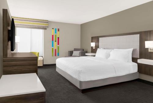 a hotel room with a large bed and a chair at Hampton Inn Olathe in Olathe