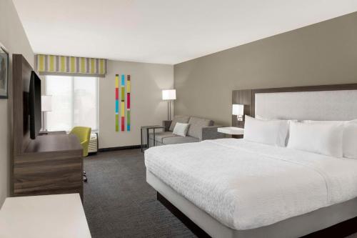 a hotel room with a bed and a couch at Hampton Inn Olathe in Olathe