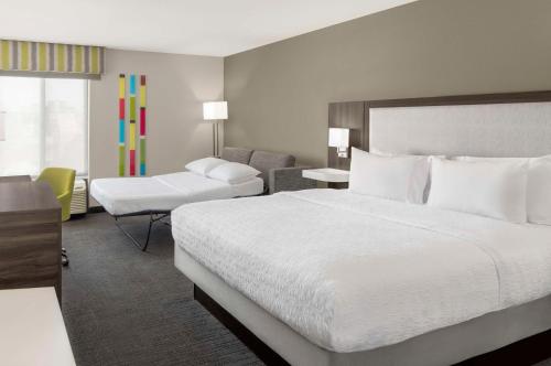 a hotel room with a large bed and a chair at Hampton Inn Olathe in Olathe