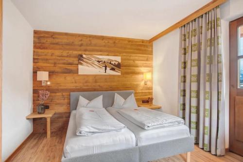 a bedroom with a bed with a wooden wall at Gästehaus Panorama - Appartement 5 in Reit im Winkl