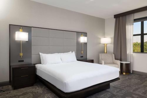 a bedroom with a large white bed and a chair at Hilton Promenade Branson Landing in Branson