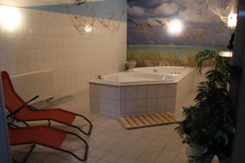 ein Badezimmer mit einer Badewanne, einem Stuhl und einem Gemälde in der Unterkunft Hotel Mecklenburger Mühle Garni in Wismar