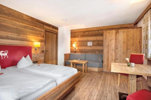 a bedroom with a bed and a table and a chair at Gästehaus Panorama - Appartement 4 in Reit im Winkl