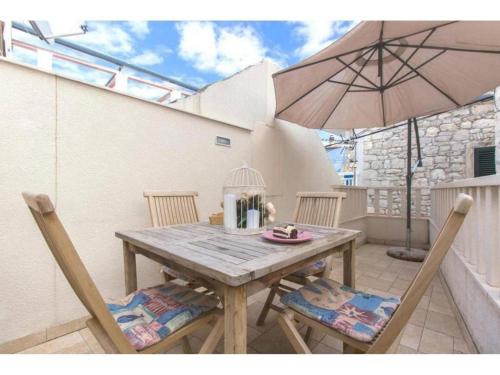 einen Holztisch mit zwei Stühlen und einem Sonnenschirm in der Unterkunft Stone Apartment Primosten in Primošten
