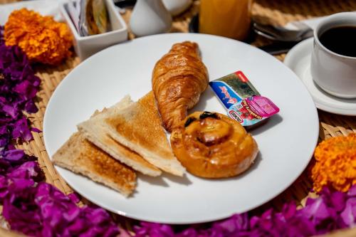 a plate of food with a pastry and bread and a cup of coffee at The Macaw Ubud Green Uma Villa in Blahbatu