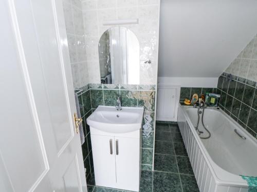 a bathroom with a tub and a sink and a tub and a mirror at Bayview in Belmullet
