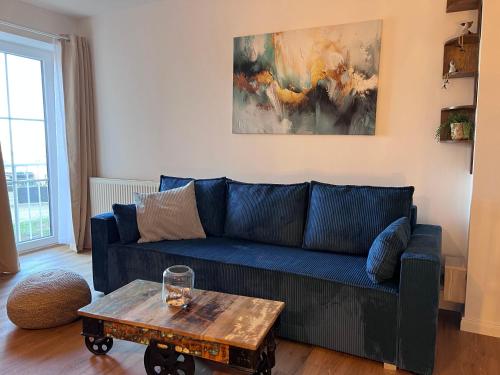 a living room with a blue couch and a table at Familienwohnung-Harbour-View in Orth