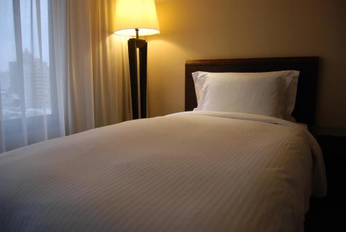 a bedroom with a white bed with a lamp and a window at Century Hotel Taoyuan in Taoyuan