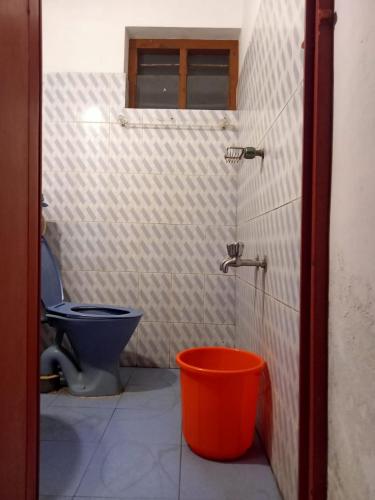 a bathroom with a toilet and a bucket at The Lungi Vibe in Varkala