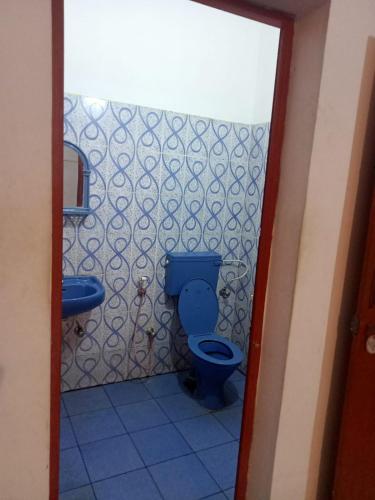 a bathroom with a blue toilet and a sink at The Lungi Vibe in Varkala