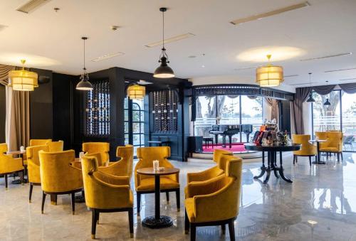 a dining room with yellow chairs and tables at Green Dragon Boutique Hotel in Cẩm Phả
