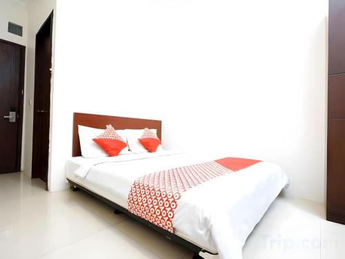 a bedroom with a bed with red and white pillows at Hotel O Pasteur Near Nuart Sculpture Park Formerly Maleo Exclusive in Bandung