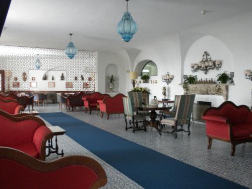 ein Wohnzimmer mit roten Stühlen und einem blauen Teppich in der Unterkunft Arathena Rocks Hotel in Giardini-Naxos