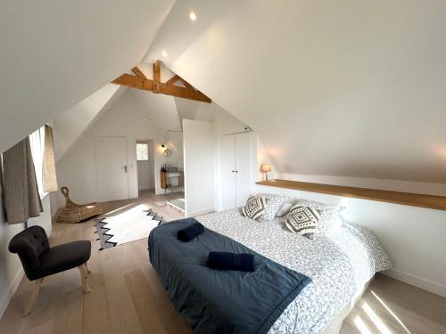 une chambre avec un lit et une chaise dans un grenier dans l'établissement La Villa Bretonniere - Piscine & SPA - 9p, à Notre-Dame-de-Courson
