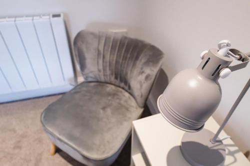 a gray chair and a lamp on a table at Anne's Place in Boat of Garten