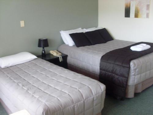 a hotel room with two beds and a table with a lamp at Motel 22 in Lower Hutt