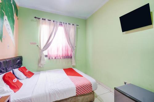 a bedroom with a bed and a television and a window at Hotel O Tebet Near Tebet Station Formerly Sabda Guest House in Jakarta