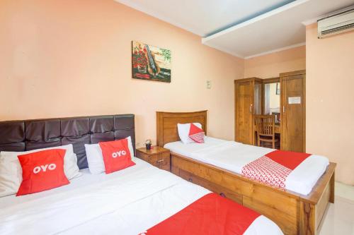 two beds in a room with red and white pillows at Hotel O Tebet Near Tebet Station Formerly Sabda Guest House in Jakarta